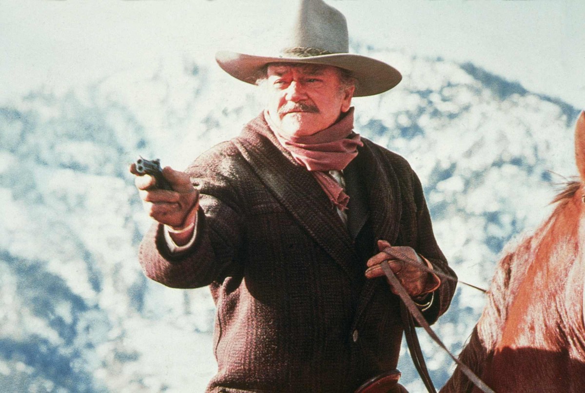 'The Shootist' John Wayne as J.B. Books riding a horse holding out his gun